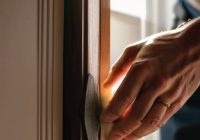 Man weatherstripping a door to save energy.